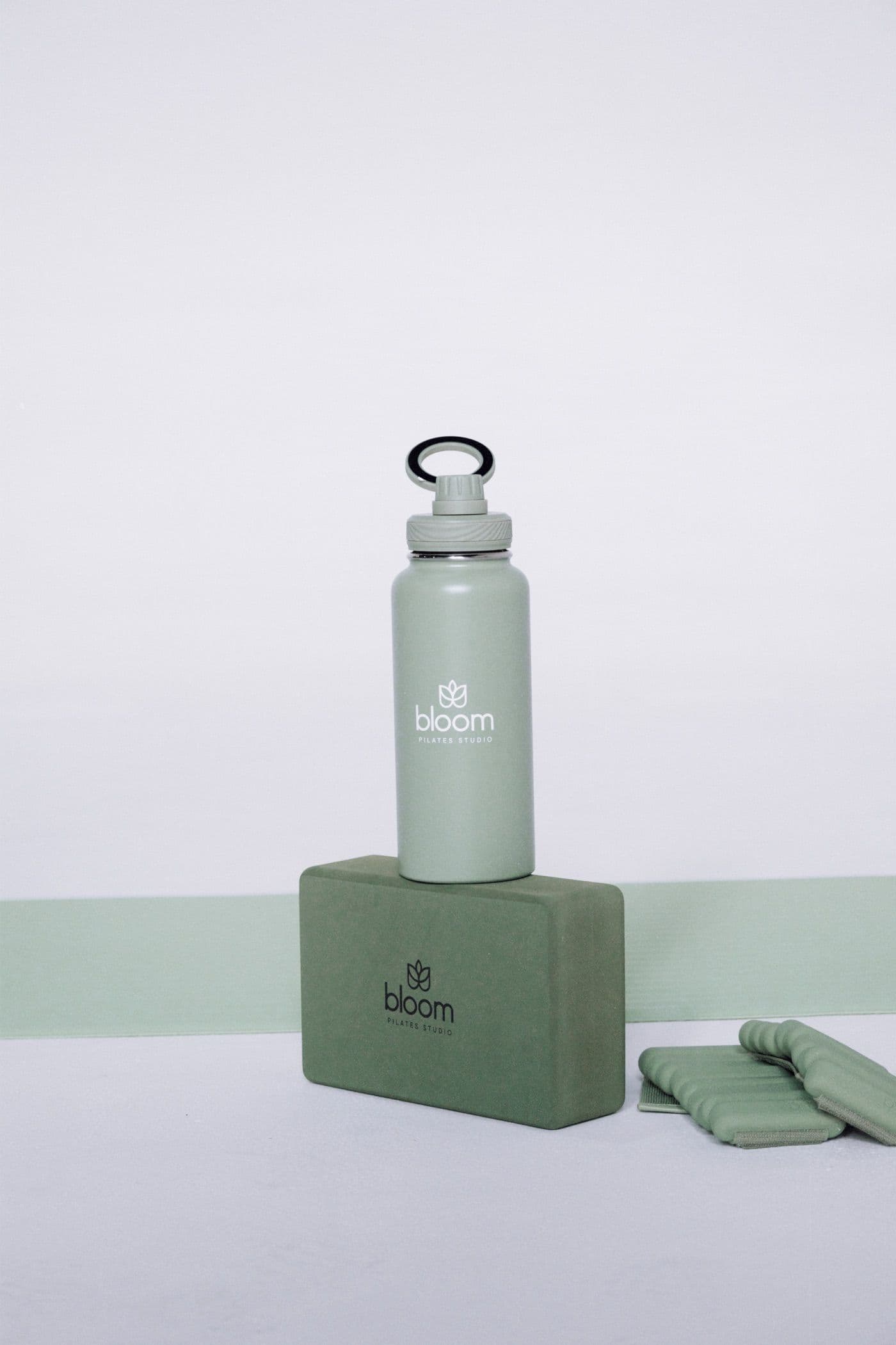 Botella y bloque sage con el logo de Bloom sobre el mat